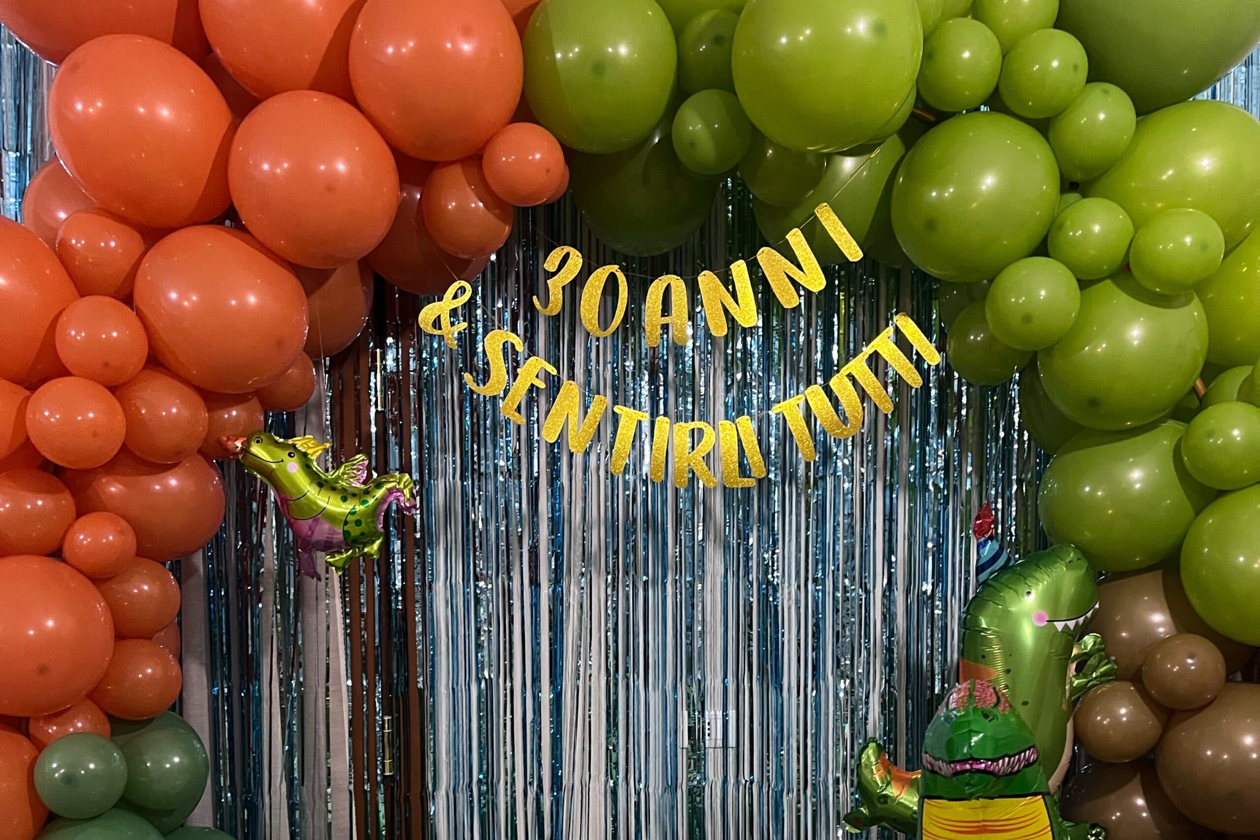 Compleanno a tema dinosauri con palloncini arancio e verdi